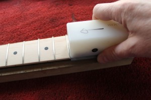 A Stewart Macdonald fret beveling file is used to dress the fret ends