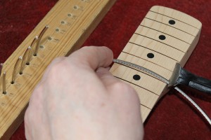 The fret wire is cut to length using pincers