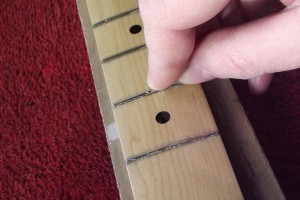 Scraping lacquer from the frets using a modified round-headed nail